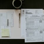 Invoice paperwork and a pen on a desk beside a cup of coffee