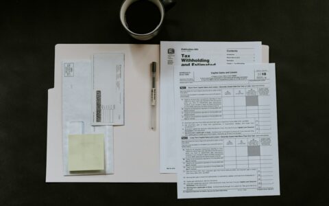 Invoice paperwork and a pen on a desk beside a cup of coffee