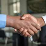 Two people shaking hands across a desk after a sales conversation