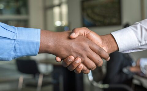 Two people shaking hands across a desk after a sales conversation