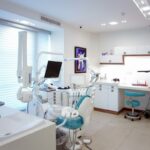 A modern dental treatment room with a chair and clinical equipment