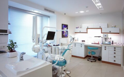 A modern dental treatment room with a chair and clinical equipment