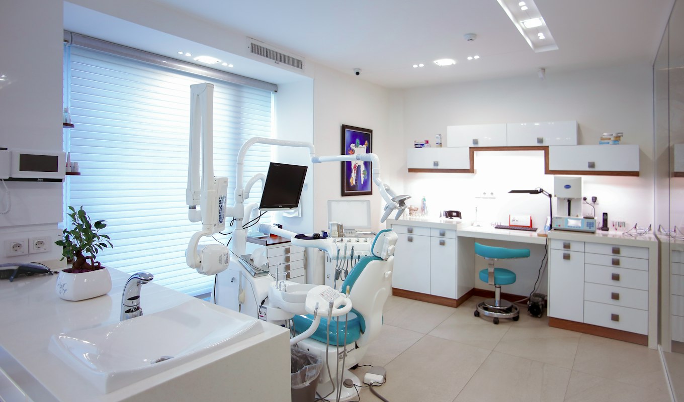 A modern dental treatment room with a chair and clinical equipment