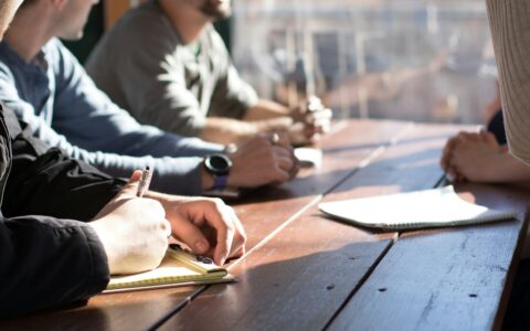 Three people reviewing documents together around a table in an office