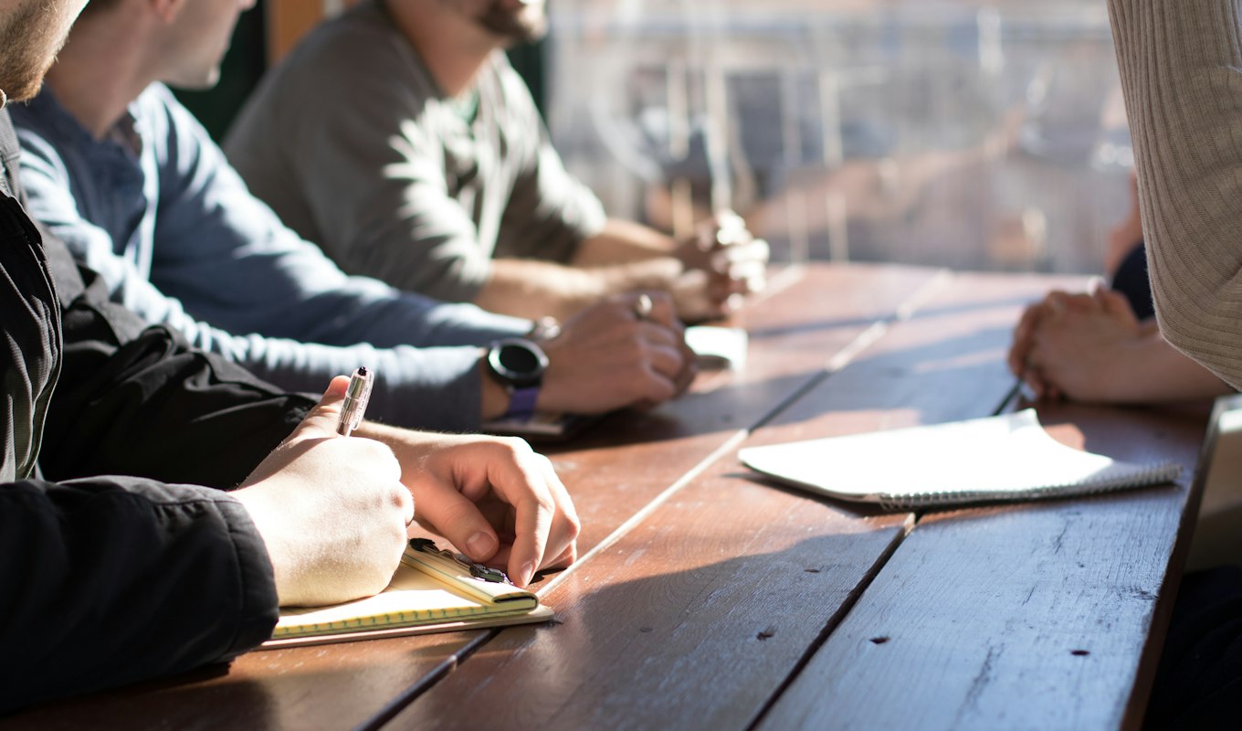 Three people reviewing documents together around a table in an office