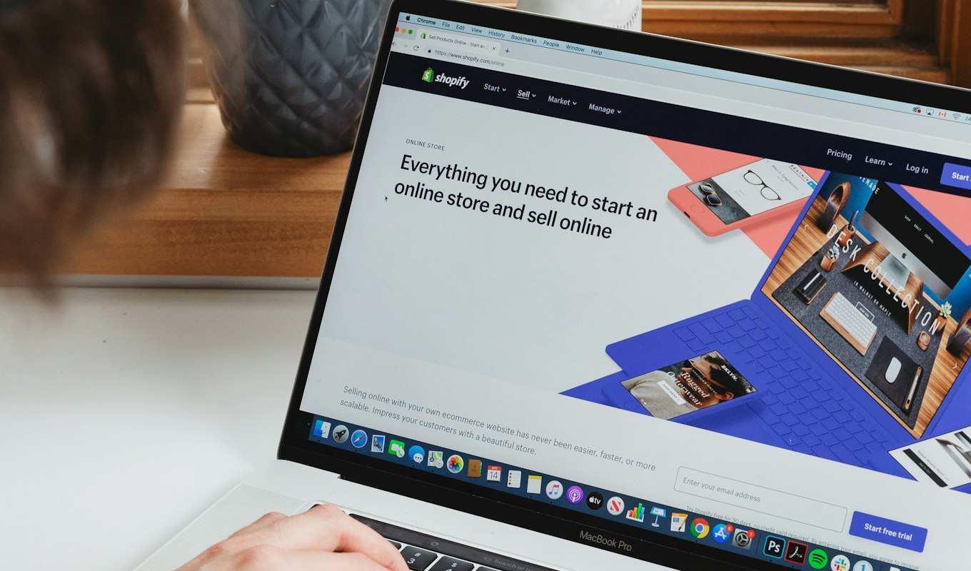 A laptop on a white desk showing an online store being set up